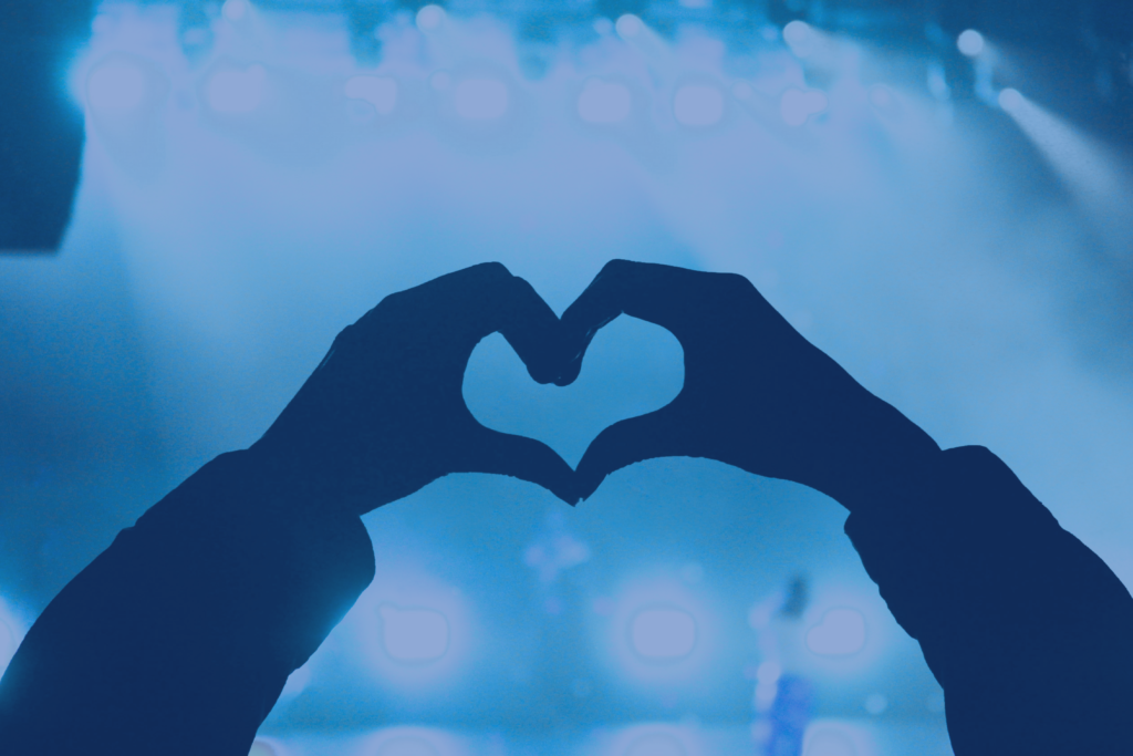 hands in the shape of a heart with blue background.